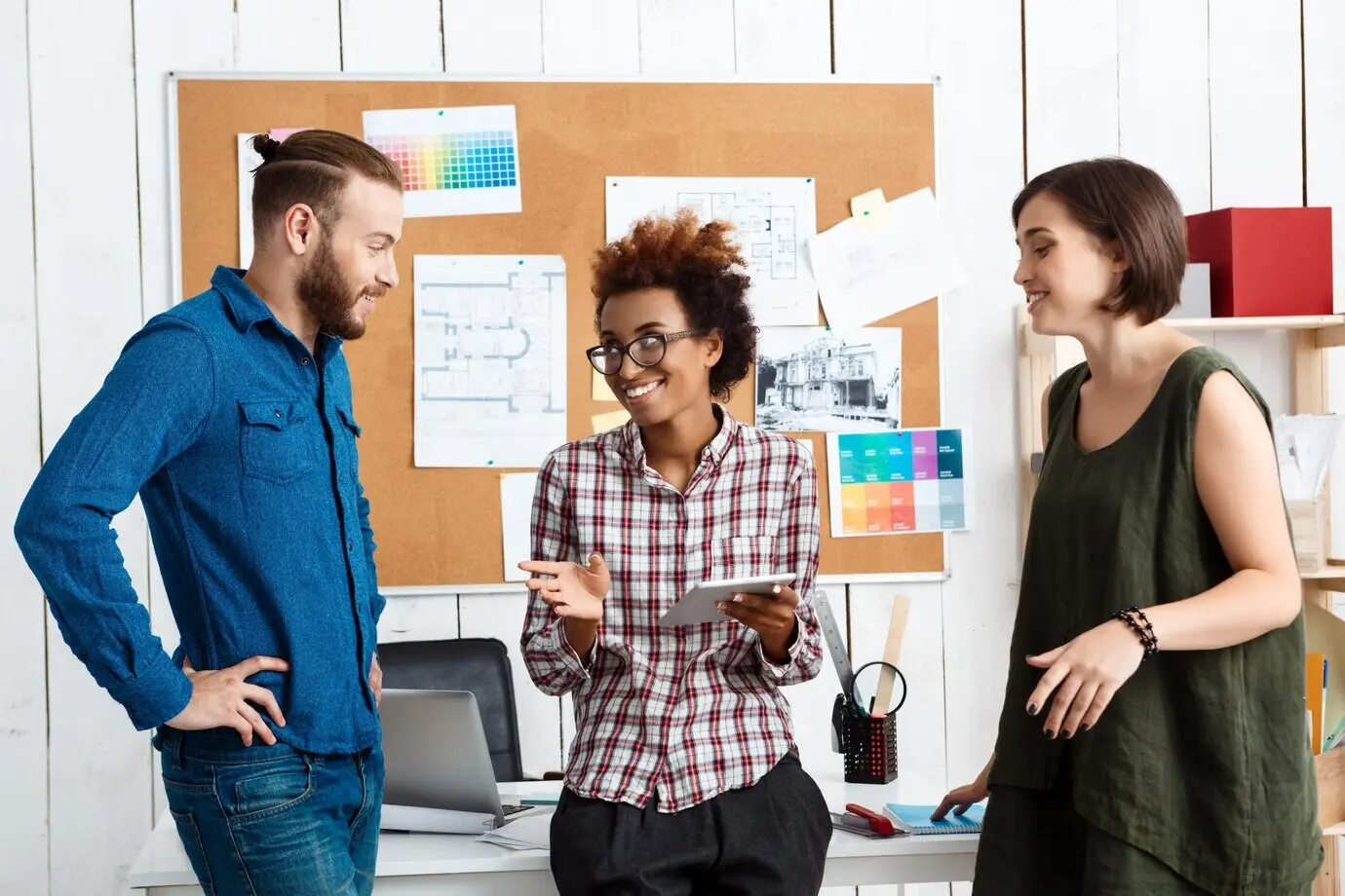 В офисе коллеги улыбаются, беседуют и обсуждают новые идеи.